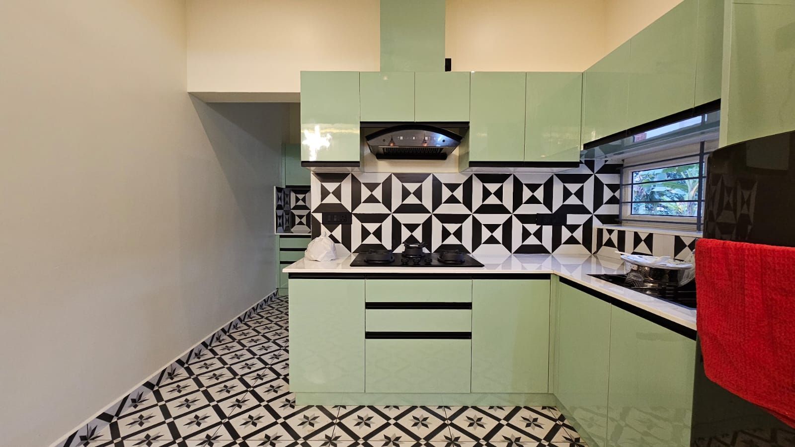 Detail shot of the kitchen workspace highlighting the L-shaped layout, integrated appliances, and the striking visual rhythm of the monochromatic tile backsplash.