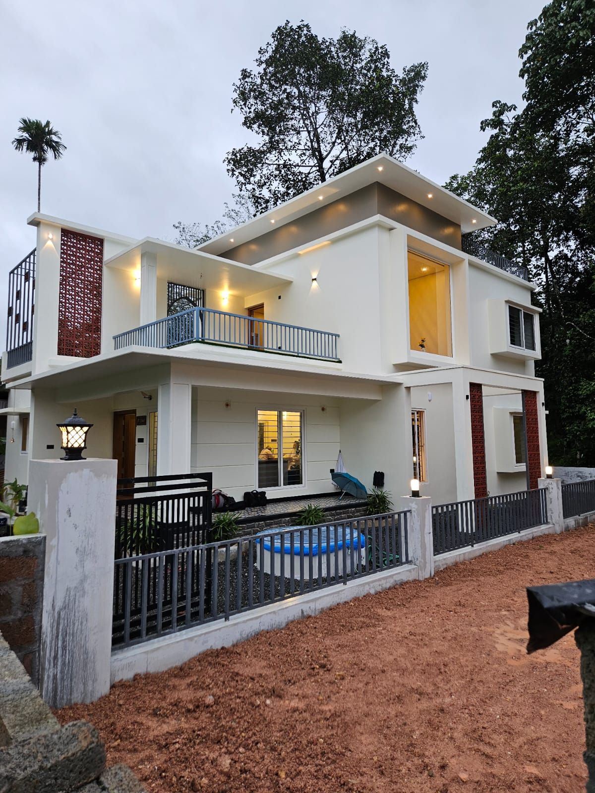 Wide angle exterior perspective of the home's front yard and fencing, emphasizing the clean architectural lines and upper-level balcony design.
